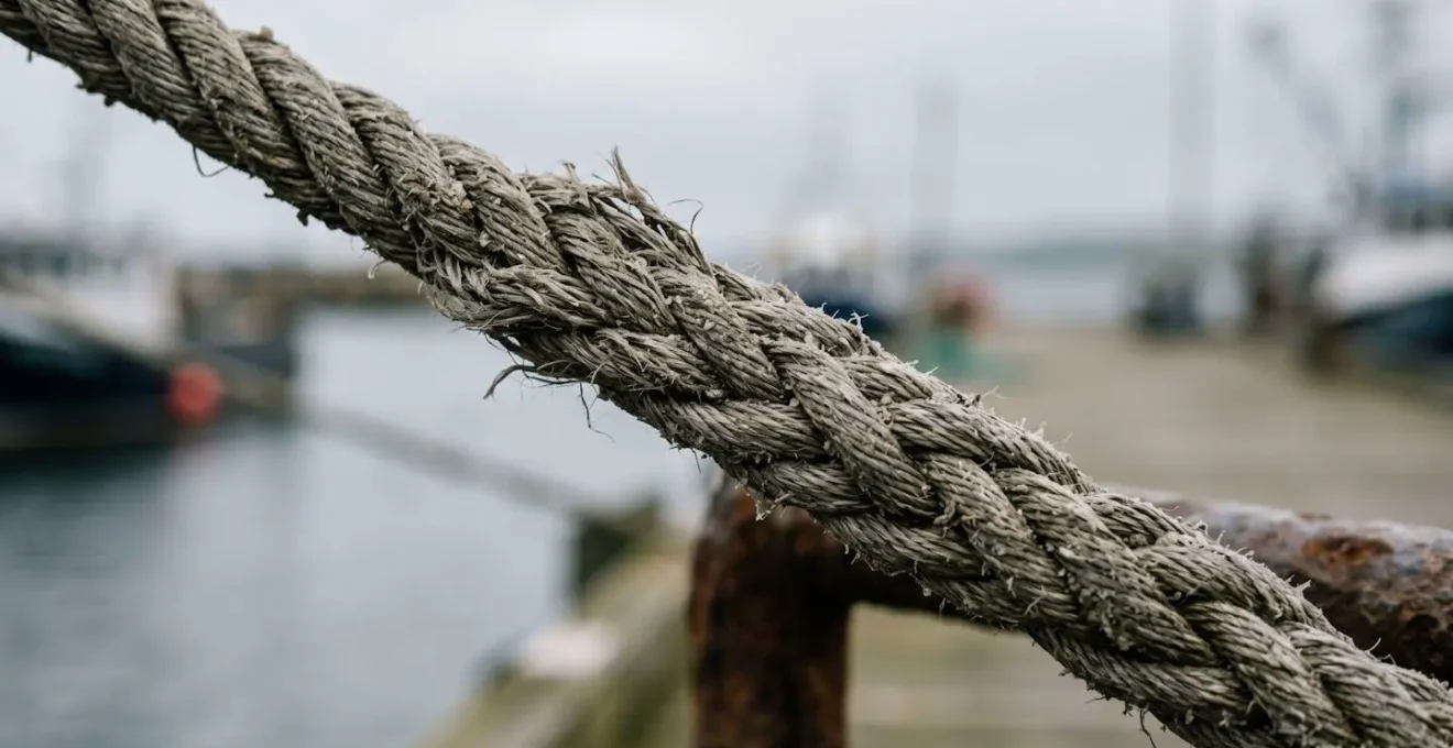 Gros plan sur une amarre de voilier sous tension extrême lors d'une houle portuaire avec détails de la texture des fibres
