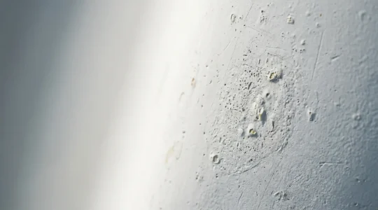 Détail macro d'une coque de voilier montrant la texture du gelcoat et les premiers signes d'hydrolyse