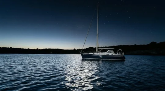 Voilier au mouillage balancé par la houle nocturne sous un ciel étoilé